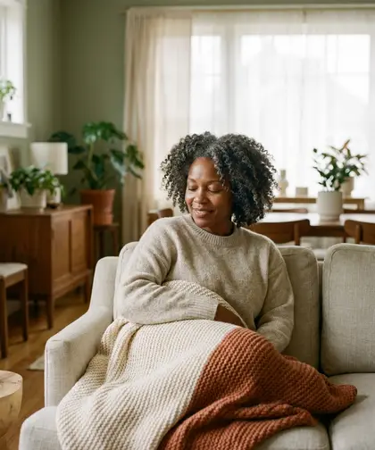 A woman resting on a sofa wrapped in a soft knit throw